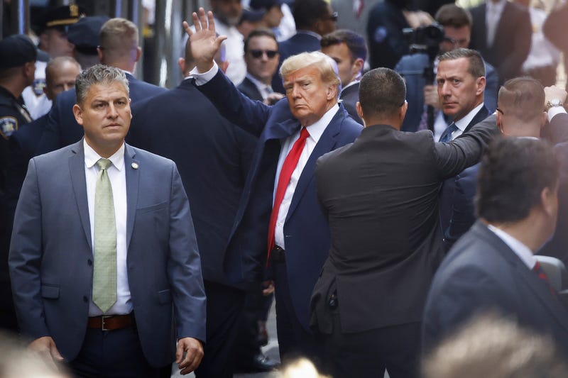Former President Donald Trump waves as he arrives at Manhattan Criminal Court for his arraignment hearing on April 4, 2023