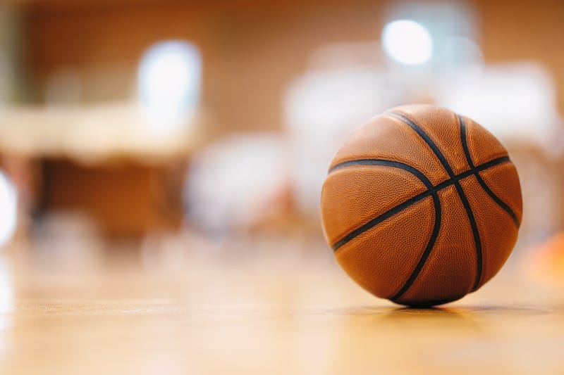 A basketball sits on an empty court.