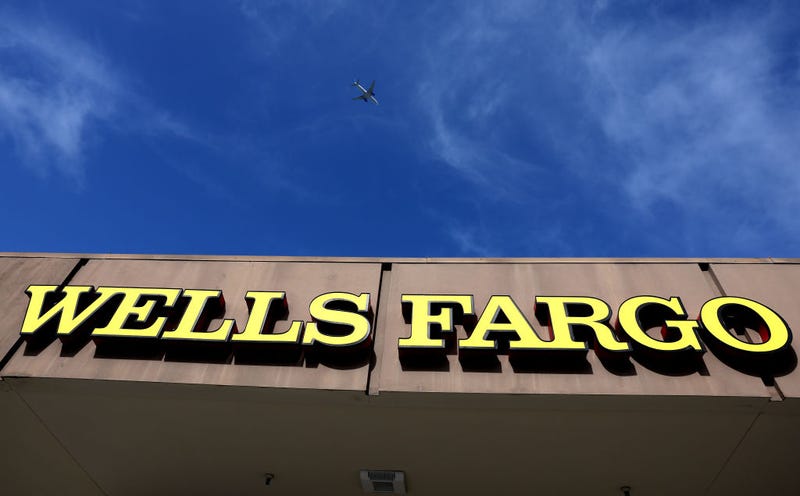 A plane flies over a sign posted on the exterior of a Wells Fargo Bank on April 14, 2023 in Daly City, California. 