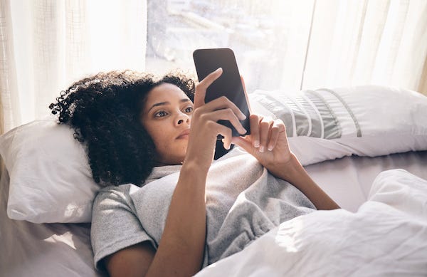 Woman looking at her phone while laying in bed