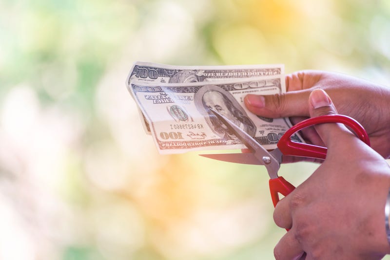 Close up hand cutting money usd banknote. Woman hand cuts money debt with scissors. Close up Hands holding scissors cutting 100 USD money bill. Businessman reduce cost discount