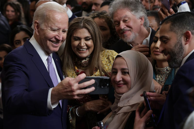 Joe Biden (L) takes selfies with guests during a reception celebrating Eid-al-Fitr in the East Room of the White House on May 1, 2023 in Washington, D.C