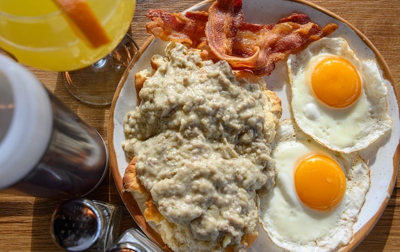 Biscuits and gravy, bacon, eggs, and a mimosa served during br