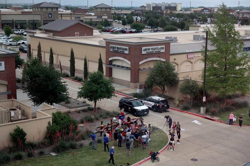 People gather around a memorial at one of the entrances to the Allen Premium Outlets mall on May 7, 2023, in Allen, Texas. According to reports, a shooter opened fire at the outlet mall, killing eight people. The gunman was then killed by an Allen Police officer that was responding to an unrelated call.