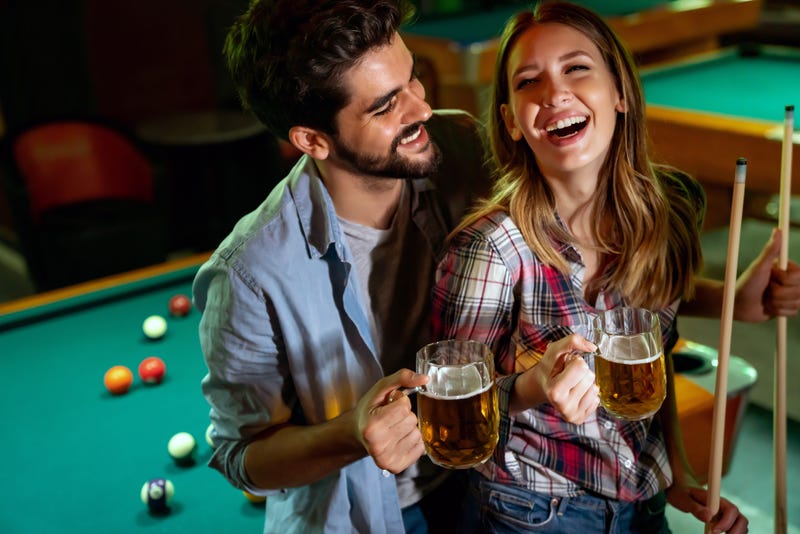 Stock image of young couple laughing while drinking beer