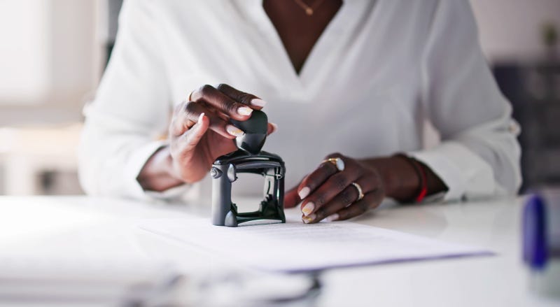 A Black woman working as a notary public with a stamp
