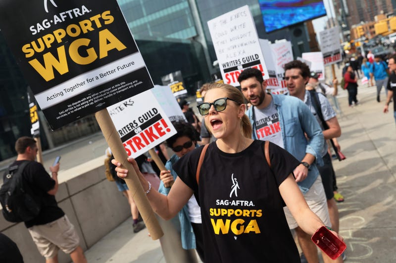 people on picket line with signs that say sag-aftra supports wga and writers guild on strike