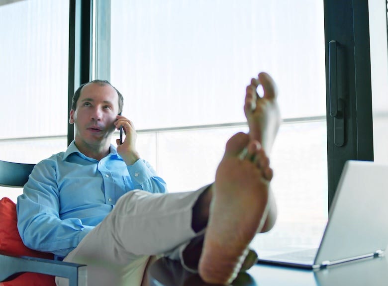 Barefoot man at the office with his feet propped up on a desk