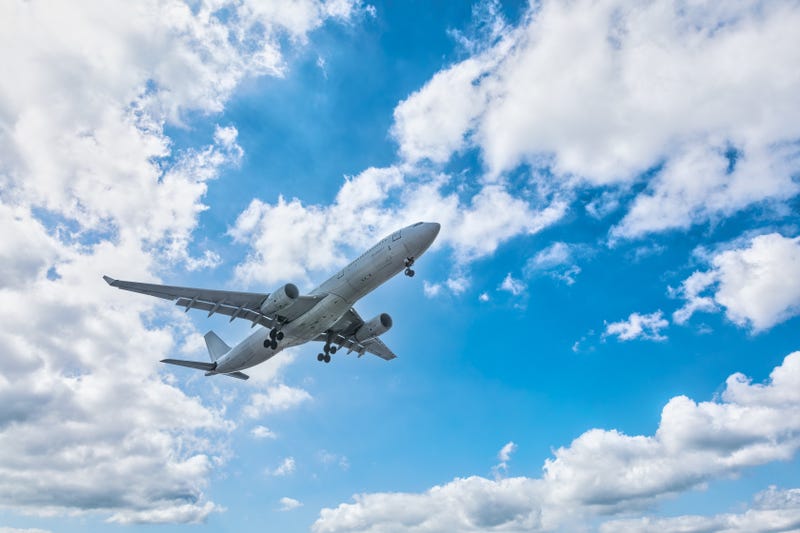 Commercial airplane flying in blue sky.