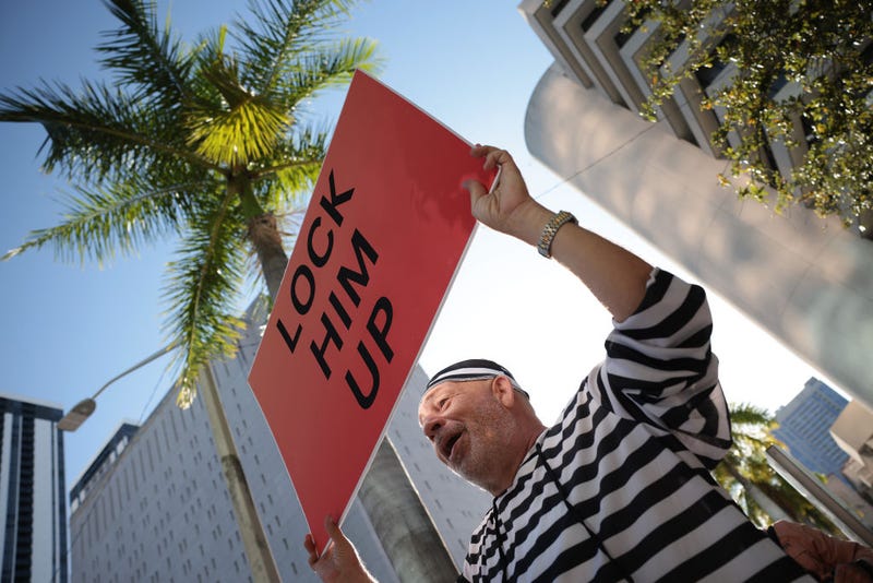 Domenic Santana holds a "Lock Him Up" sign outside the the Wilkie D. Ferguson Jr. United States Federal Courthouse. 