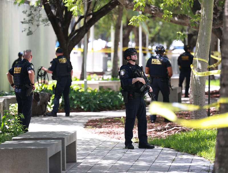 police officers stand in plaza lined with police tape