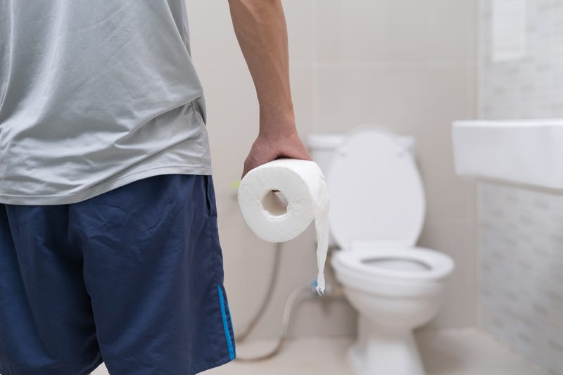 man holding toilet paper in the bathroom