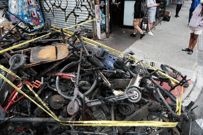 Charred remains of e-bikes and scooters sit outside of a building in Chinatown after four people were killed by a fire in an e-bike repair shop overnight on June 20, 2023 in New York City.