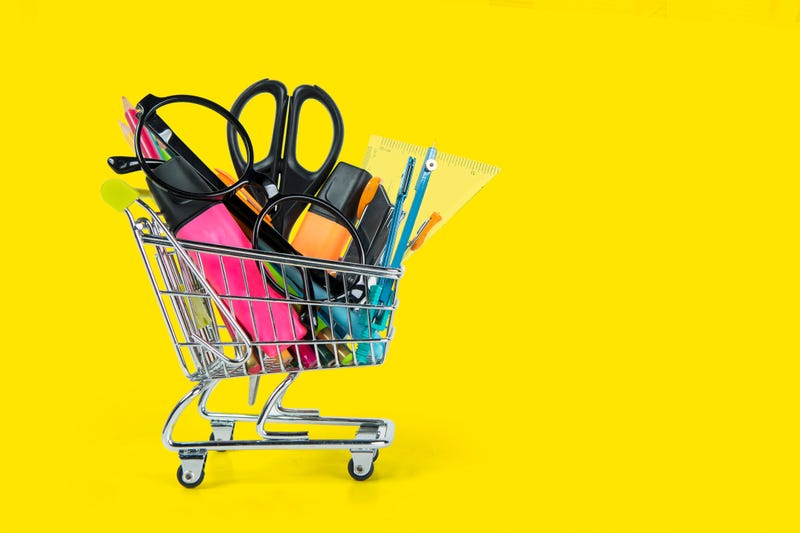 stationery inside a shopping trolley isolated over yellow background