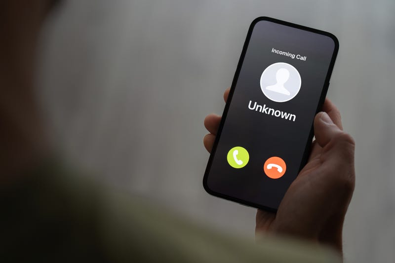 Person holding smart phone with unknown caller on the screen, probably scam