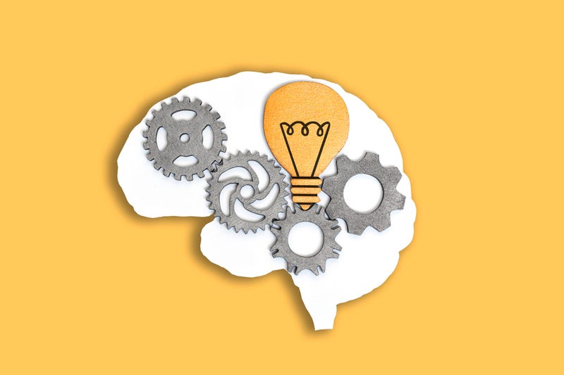 Close-up of a human brain outline with wooden gears and lightbulb isolated on yellow background.