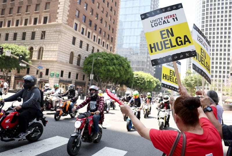 workers on picket line as motorcycles pass