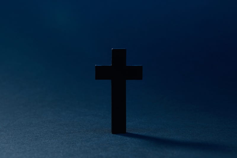 Mysterious classic dark cross isolated on the dark solid fond blue background