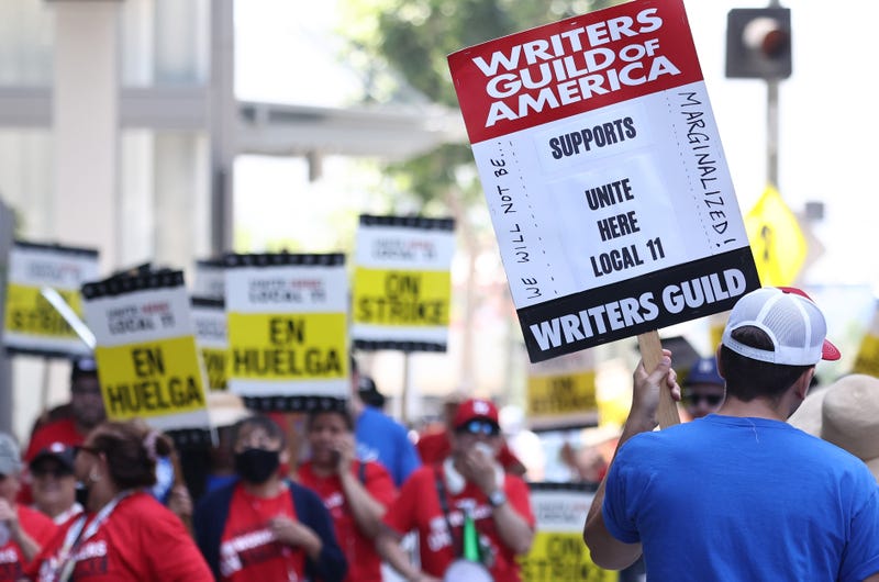 man with sign that says writers guild of america supports unite here local 11
