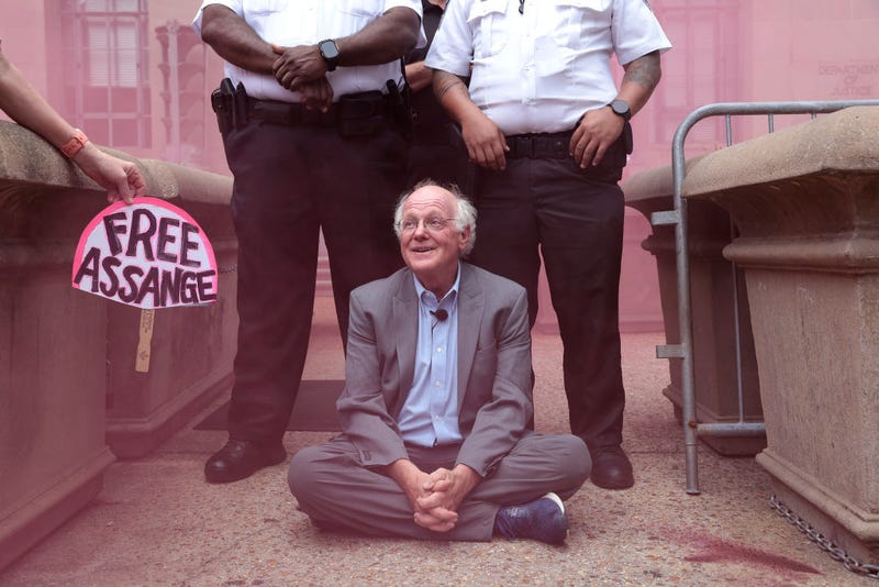 As a pink smoke bomb clouds the air, Ben Cohen, co-founder of Ben & Jerry’s ice cream, refuses to leave an entrance outside the Department of Justice before being arrested July 6, 2023 in Washington, DC. 