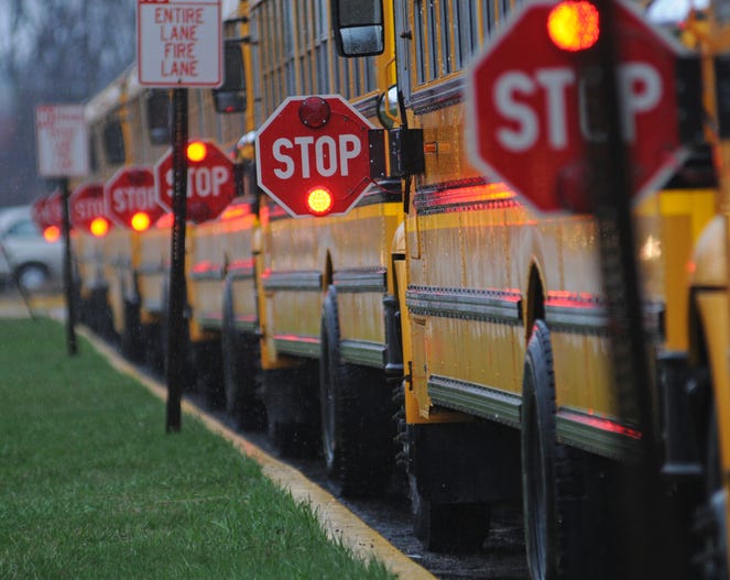 Line of school buses with Stop signs flashing. STOCK IMAGE