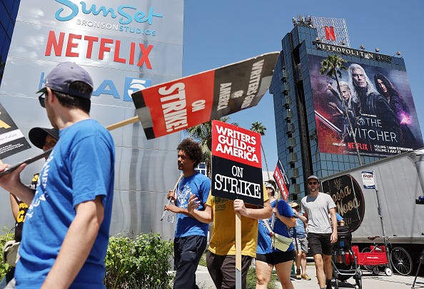 People carry signs as SAG-AFTRA members walk the picket line in solidarity with striking WGA (Writers Guild of America) workers outside Netflix offices on July 11, 2023 in Los Angeles, California.