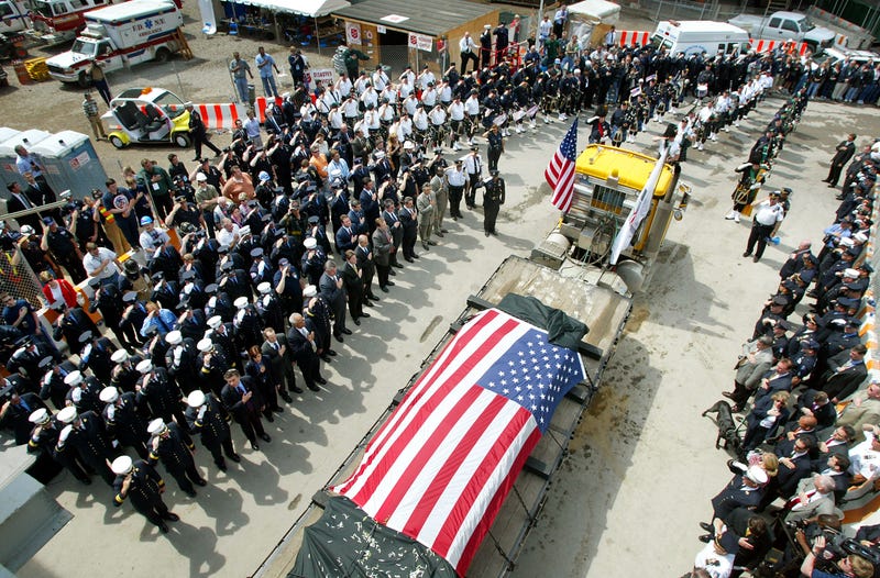Members of the FDNY and NYPD salute as a truck carrying the last steel column from the World Trade Center is removed from ground zero on May 30, 2002 in Lower Manhattan