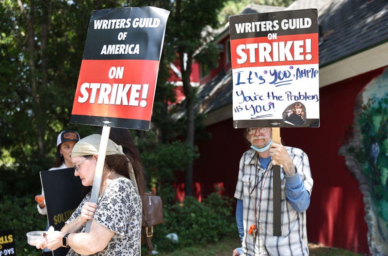 People hold signs in support of striking WGA (Writers Guild of America) members on Day 5 outside Warner Bros. Studio on July 17, 2023 in Burbank, California.