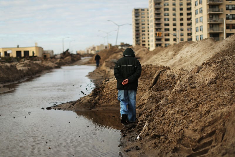 People walk on Nov. 2, 2012, through Rockaway, Queens, where a large section of the iconic boardwalk was washed away