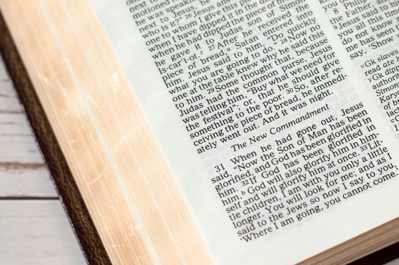 New commandment verse in open holy bible book with golden pages. Close-up. Christian love, growth, and obedience to God Jesus Christ, biblical concept.