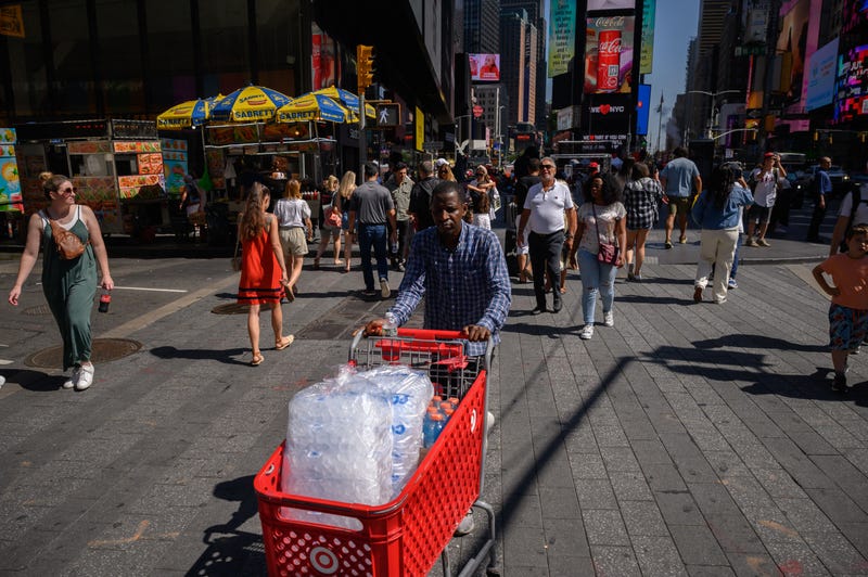 A man pushes a cart filled with ice through Times Square on July 28, 2023