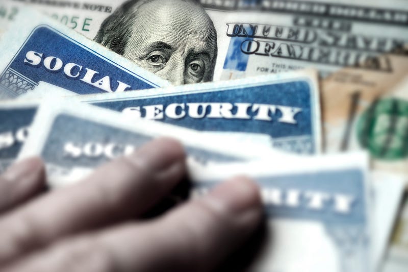 Several Social Security Cards on a US United States one hundred dollar bill $100 system of benefits for retired elderly people