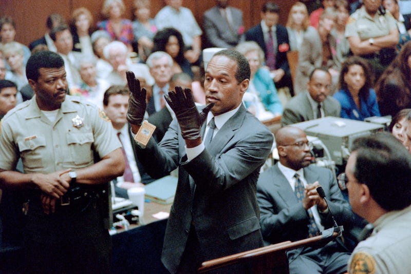 O.J. Simpson looks at a new pair of Aris extra-large gloves which the prosecutors had him put on for the jury 21 June 1995 during his double murder trial in Los Angeles. The gloves were the same type found at the Bundy murder scene and the O.J. Simpson estate. 