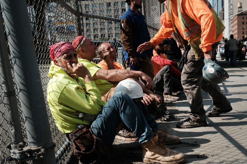 Construction workers rest at the scene of a crane collapse