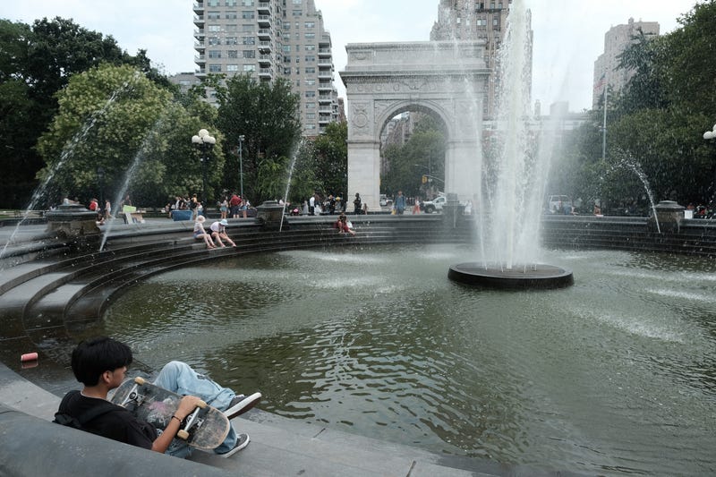 People try to keep cool by the fountain in Washington Square Park during a heat wave on July 27, 2023