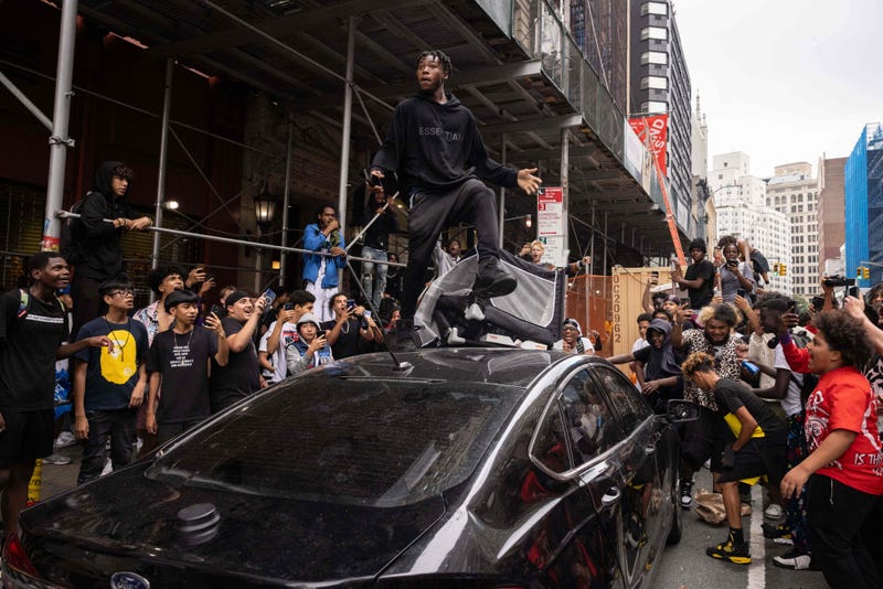 A person jumps on an NYPD vehicle during a riot in the Union Square area on Aug. 4, 2023
