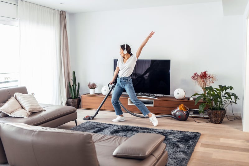 Woman cleaning with a vacuum. Happy.