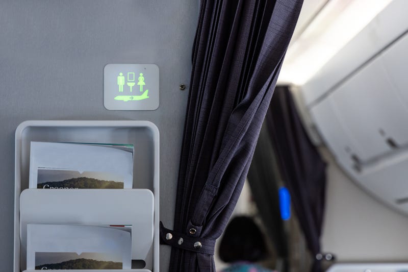 Lavatory signage on airplane cabin wall lighted green suggests it is not occupied and is available.