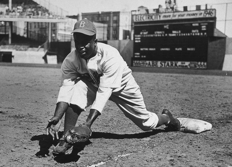 American baseball player Jackie Robinson (1919 - 1972) grounds a ball at first place while warming up for an exhibition game against the New York Yankees at Ebbets Field in New York City, circa the 1950s.