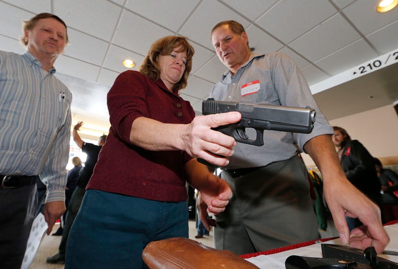 A woman is shown how to handle a handgun