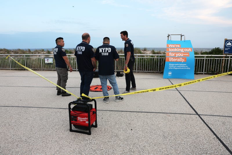 Police gather along Rockaway Beach at Beach 59th Street after a woman was attacked by a shark in the early evening on Aug. 7, 2023