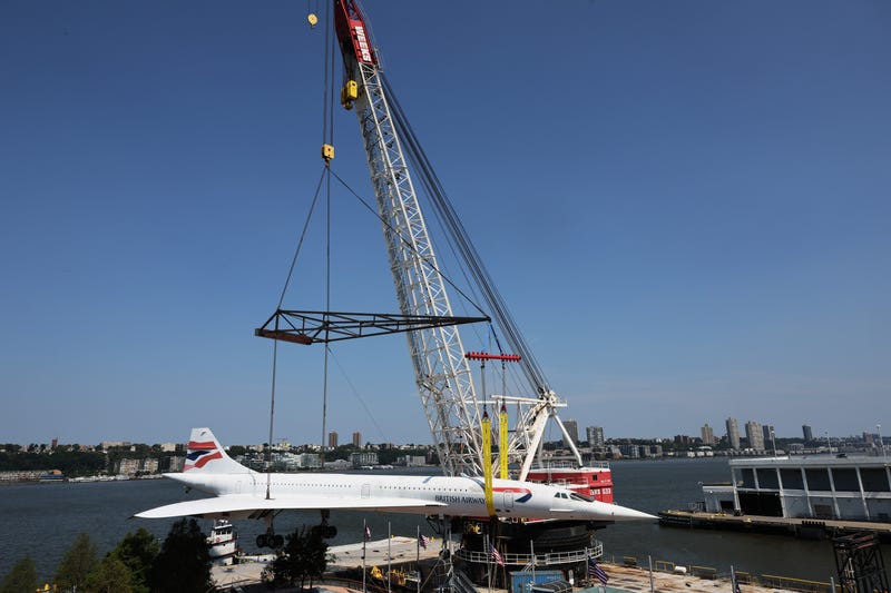 A crane prepares to lift the Concorde into the air, clearing space below.