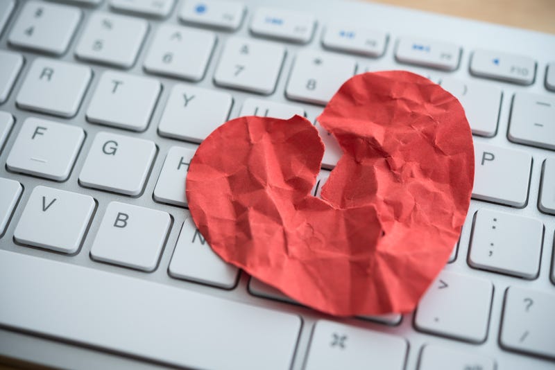 Red broken heart paper on white keyboard