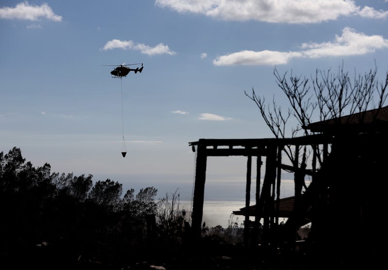 helicopter flying above land burned by wildfire