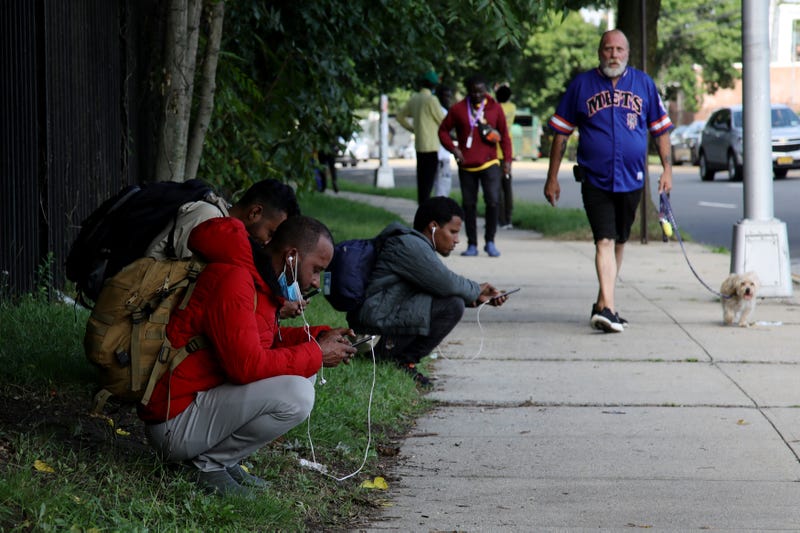 People wait outside the "tent city" for migrants at Creedmoor Psychiatric Center in Queens on Aug. 16, 2023