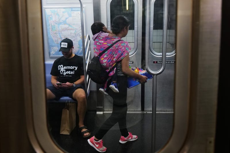 A young woman with a baby sells candy and other items in a subway car on Aug. 18, 2023. Over 100,000 migrants have arrived in the city since last spring