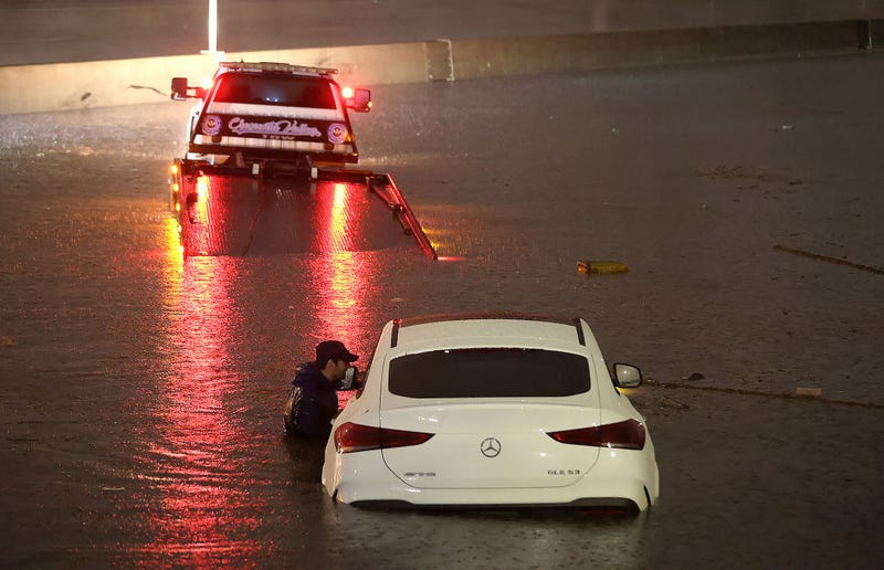 A tow truck driver attempts to pull a stranded car out of floodwaters on the Golden State Freeway as tropical storm Hilary moves through the area on August 20, 2023 in Sun Valley, California. 