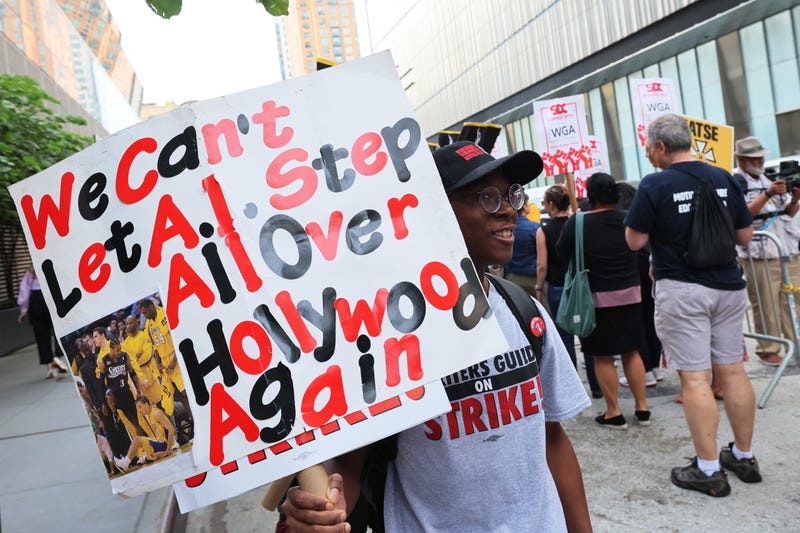 man with a sign that says we can't let AI step all over hollywood again