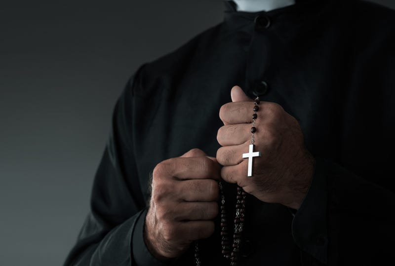 Close up of a priest holding rosary and praying with copy space