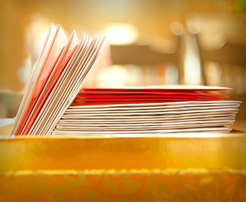 A stack of sealed red and white envelopes sit in a box 